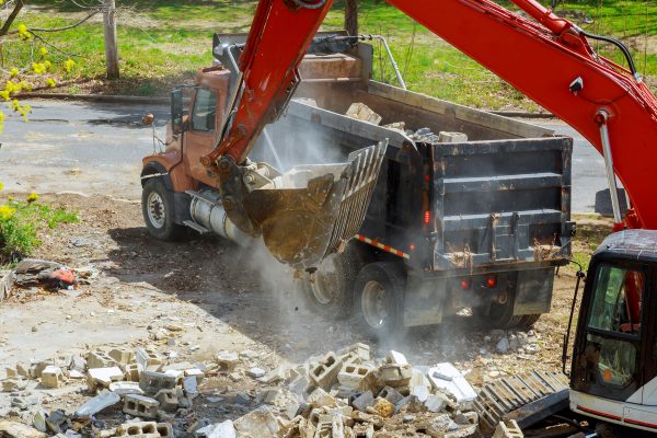 Backhoe excavator scoop loading from building in the construction debris a dump truck